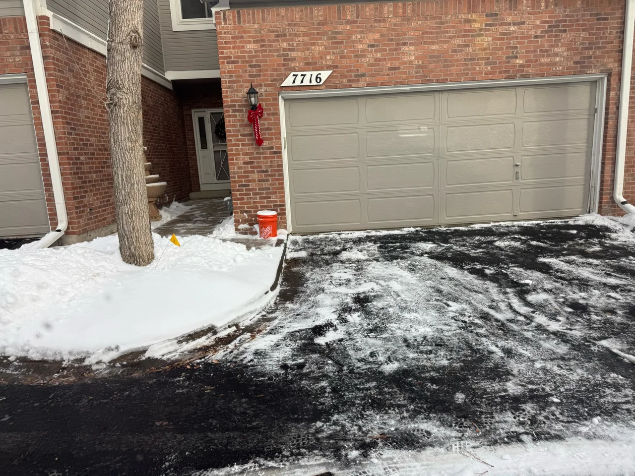 Driveway and entry path at a brick home, with some snow remaining