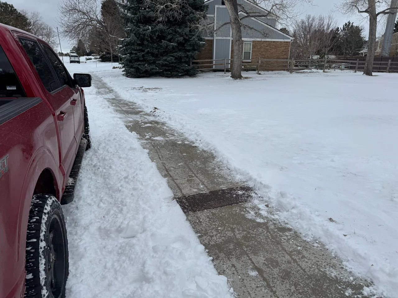 Sidewalk with snow cleared from the path beside a red truck