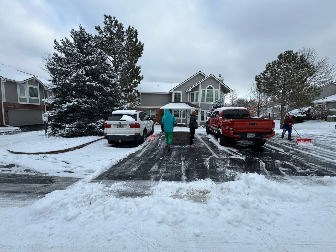 People with shovels beside residential driveways